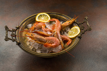 Large tiger Shrimps and slice of lemon fresh in ancient plate full of ice.