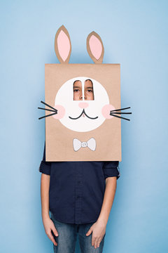 A kid in bunny paper bag mask