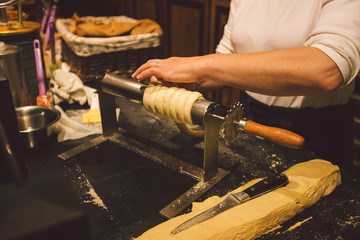 The hands of a female baker cook trdelnik or Trdlo national treat in the Czech Republic in winter