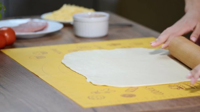 Dough for pizza and rolling-pin on wooden table