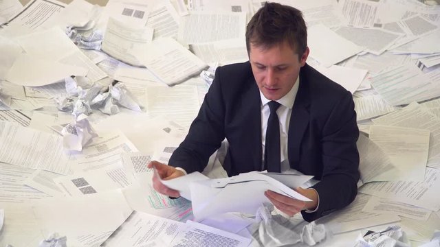 the man in the office drowning in paper