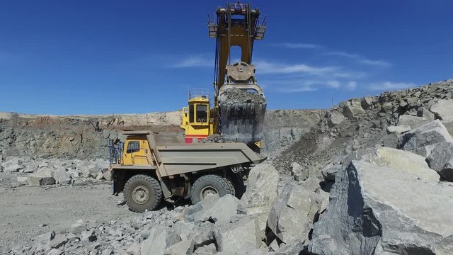 Mining. excavator loading granite or ore into dump truck