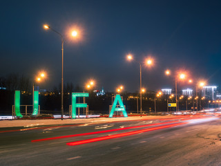 sign Ufa and transport traffic on main road into city in the winter night. Bashkortostan, Russia.