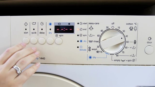 Closeup 4k footage of female hand prussing buttons and turning switch on washing machine at laundry