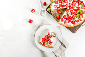 Homemade biscuit cake with whipped cream, fresh organic raw strawberries and mint. On a white stone table. Copy space top view