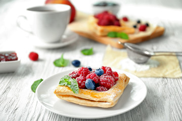 Plate with yummy berry puff pastry on wooden table