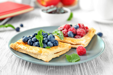 Plate with yummy berry puff pastry on wooden table