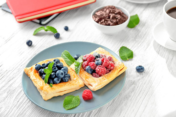 Plate with yummy berry puff pastry on wooden table