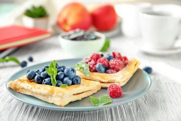 Plate with yummy berry puff pastry on wooden table