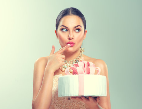 Funny joyful beauty model girl holding big beautiful party or birthday cake over green background