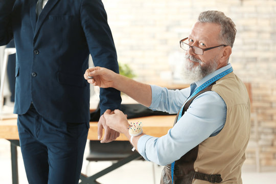 Senior man tailoring formal suit for businessman in atelier