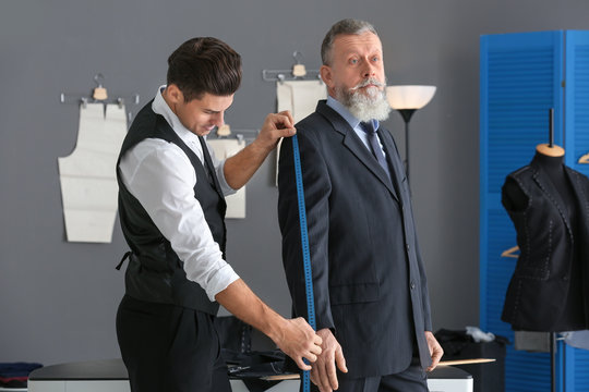 Tailor taking client's measurements in atelier