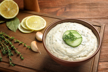 Tasty sauce with garlic in bowl on wooden board