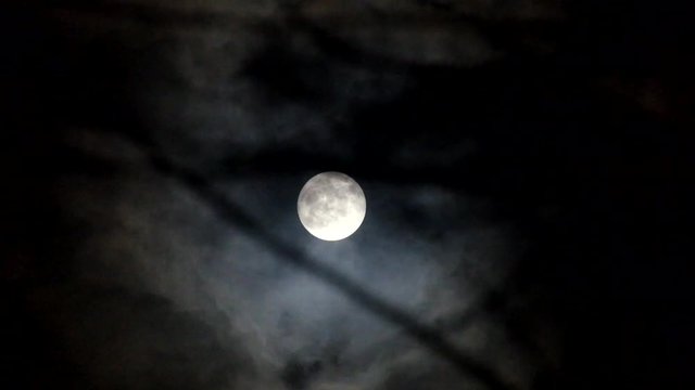Black clouds run through the night sky against the background of the cold moon
