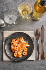 Plate with delicious fried shrimps and garlic on table