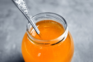 Glass jar with delicious honey on grey table