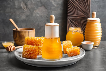 Glass jar with delicious honey and fresh honeycombs on table