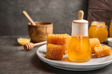 Glass jar with delicious honey and fresh honeycombs on table