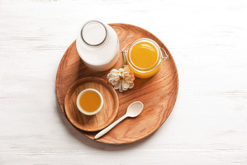 Wooden dish with milk and honey on light background, top view