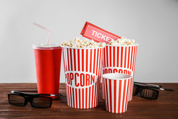 Tasty popcorn, glasses and tickets on wooden table