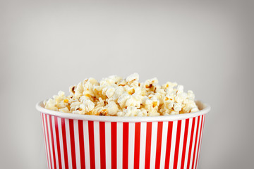 Striped bucket with tasty popcorn on light background, closeup