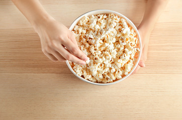 Woman eating tasty popcorn at table, top view