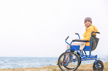 Naklejka premium Cute girl in wheelchair on sea shore