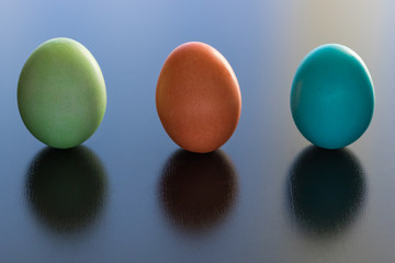 Easter eggs standing up on a shiny table