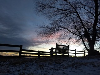 SILHOUETTE OF FENCE AND EMPTY WOODEN BENCH AT SUNSET IN THE COUNTRYSIDE COUNTRYSIDE