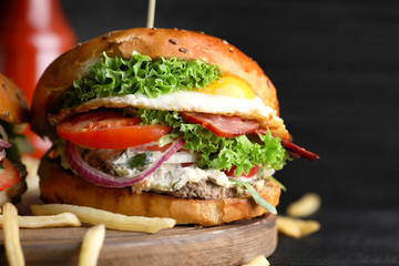 Tasty burger with fried egg on wooden board, closeup