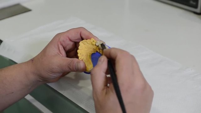 odontotecnico pulisce una forma di una dentiera