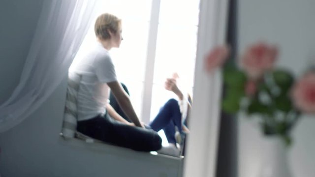 Dating couple is sitting on the window sill and emotionally discussing this day spending.