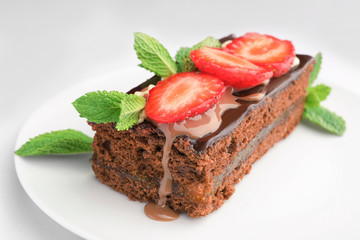 Plate with yummy chocolate cake and caramel topping on white background