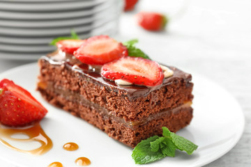 Fototapeta na wymiar Yummy chocolate cake with caramel topping and strawberry on plate, closeup