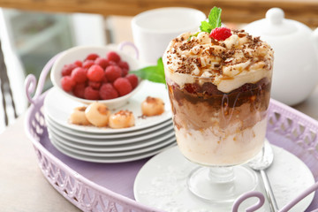 Glass with yummy caramel dessert on tray