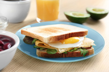 Plate with tasty toasts and fried egg on wooden table, closeup