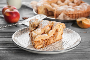 Plate with piece of delicious apple pie on wooden table