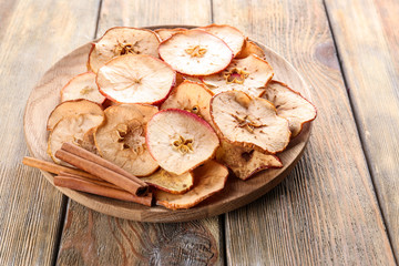 Wooden plate with tasty apple chips on table