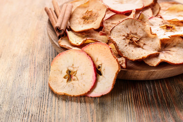 Wooden plate with tasty apple chips on table