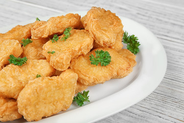 Plate with tasty chicken nuggets on table