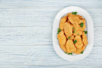 Plate with tasty chicken nuggets on table