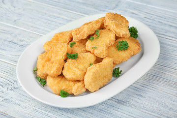 Plate with tasty chicken nuggets on table