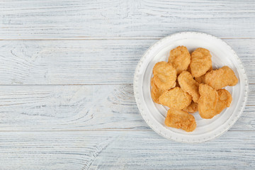 Plate with tasty chicken nuggets on table