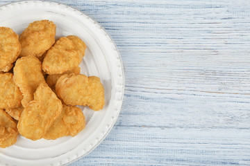 Plate with tasty chicken nuggets on table
