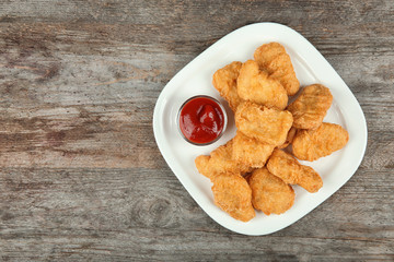 Plate with tasty chicken nuggets and sauce on table