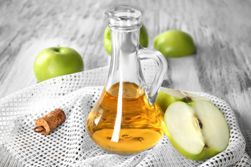 Glass jug with apple vinegar and fresh fruit on table