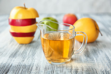 Glass jug with apple vinegar on wooden table
