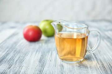 Glass jug with apple vinegar on wooden table