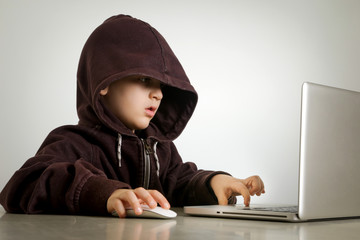 Young hacker in hoodie in front of laptop 