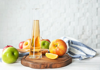 Glass bottle with apple vinegar and fresh fruit on table